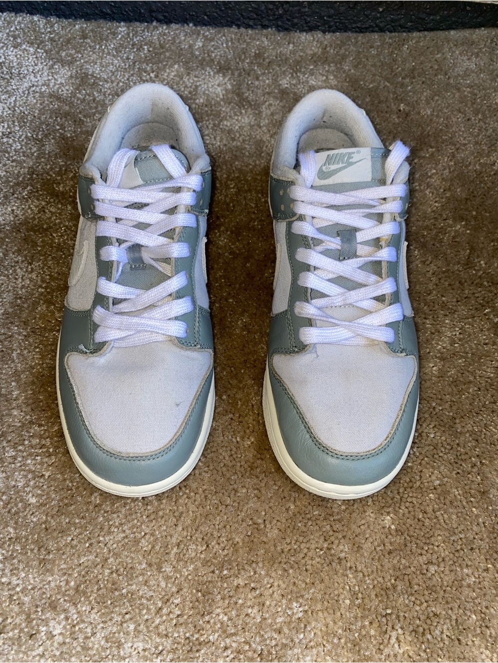 These are Nike Dunk Low sneakers in the "Mica Green" colorway, featuring